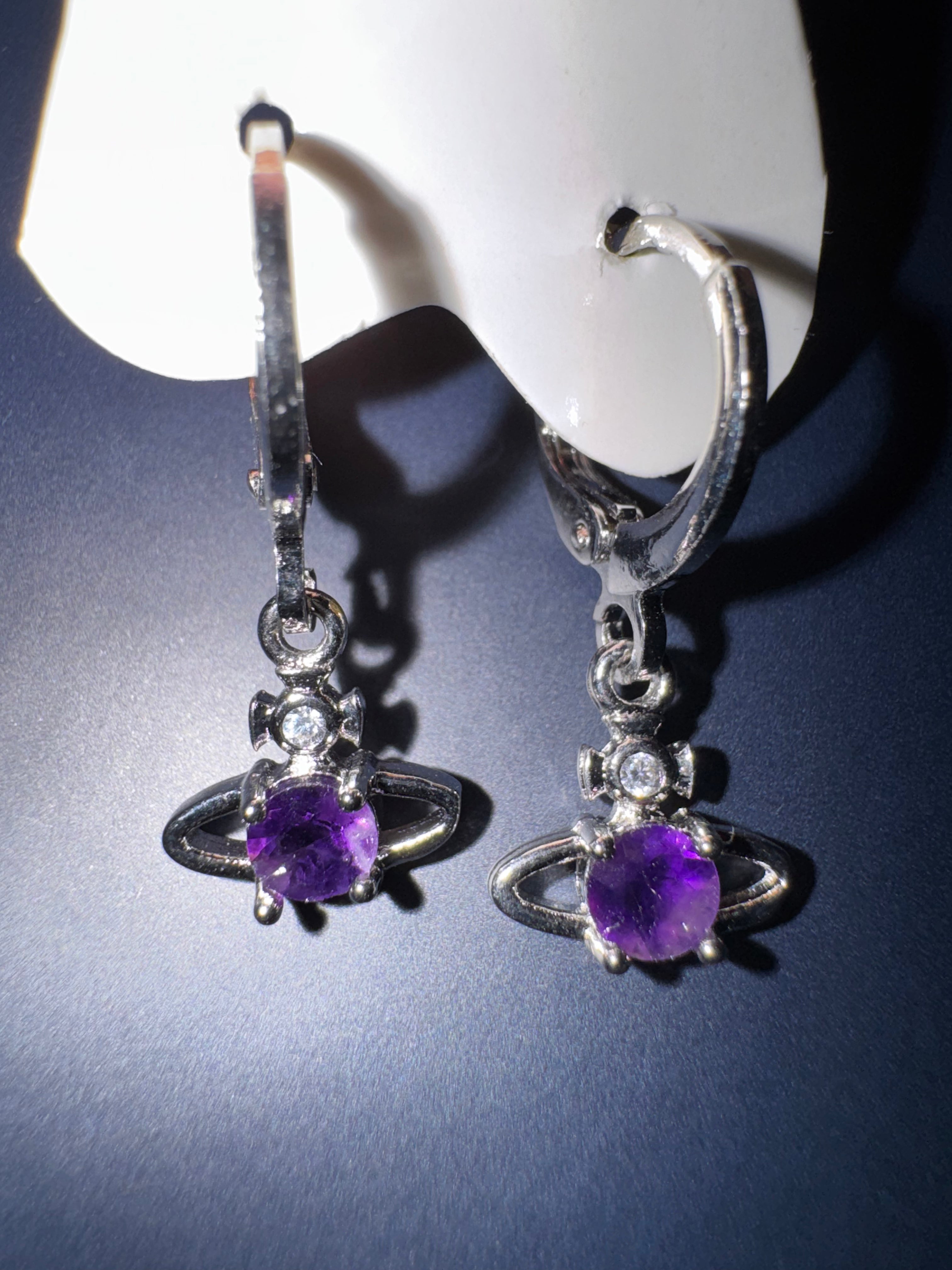 Sterling silver amethyst Saturn celestial huggie hoop earrings on a dark surface