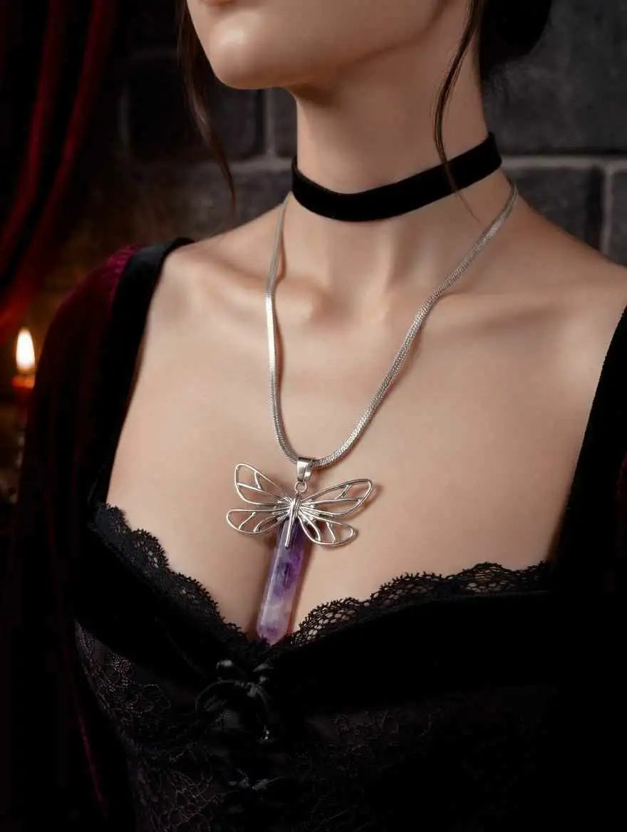 Amethyst crystal dragonfly pendant necklace on a dark surface