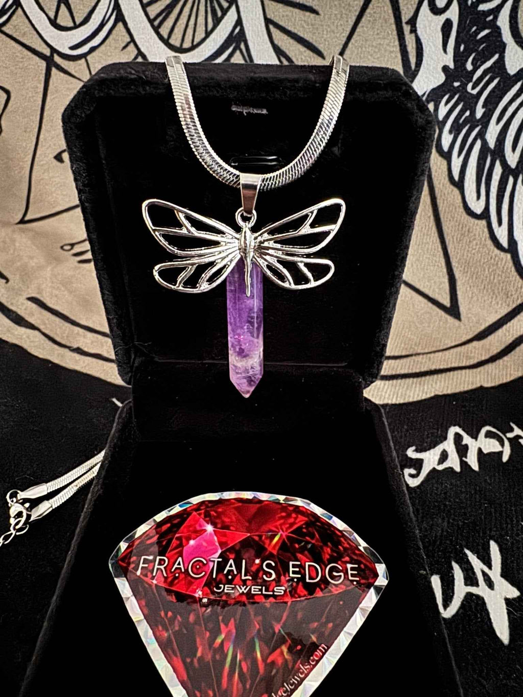 Gothic amethyst dragonfly crystal point pendant necklace resting in a black velvet jewelry box on a dark background