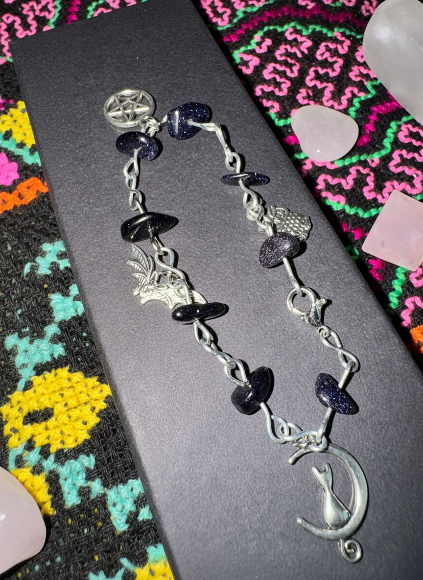 Goldstone charm bracelet with black shimmering beads and creatures of the night charms.
