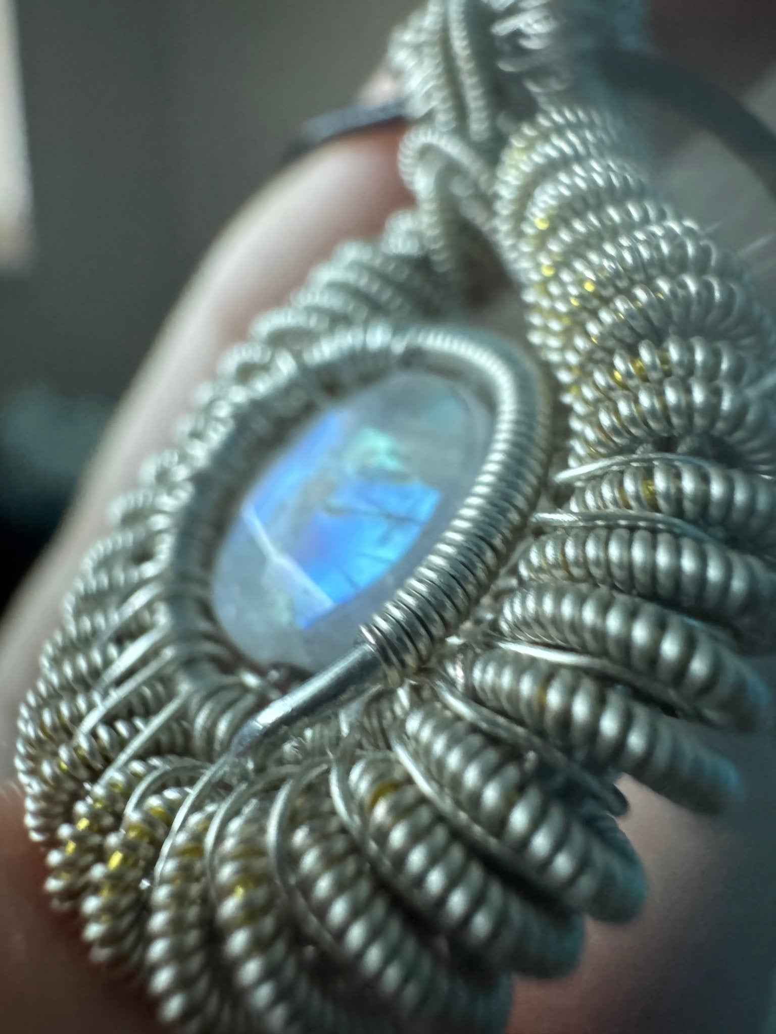 A close-up of a reversible wire wrapped moonstone pendant with a dark background.