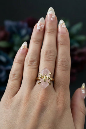 Rose quartz crystal honeybee ring with gold plated band on a dark background