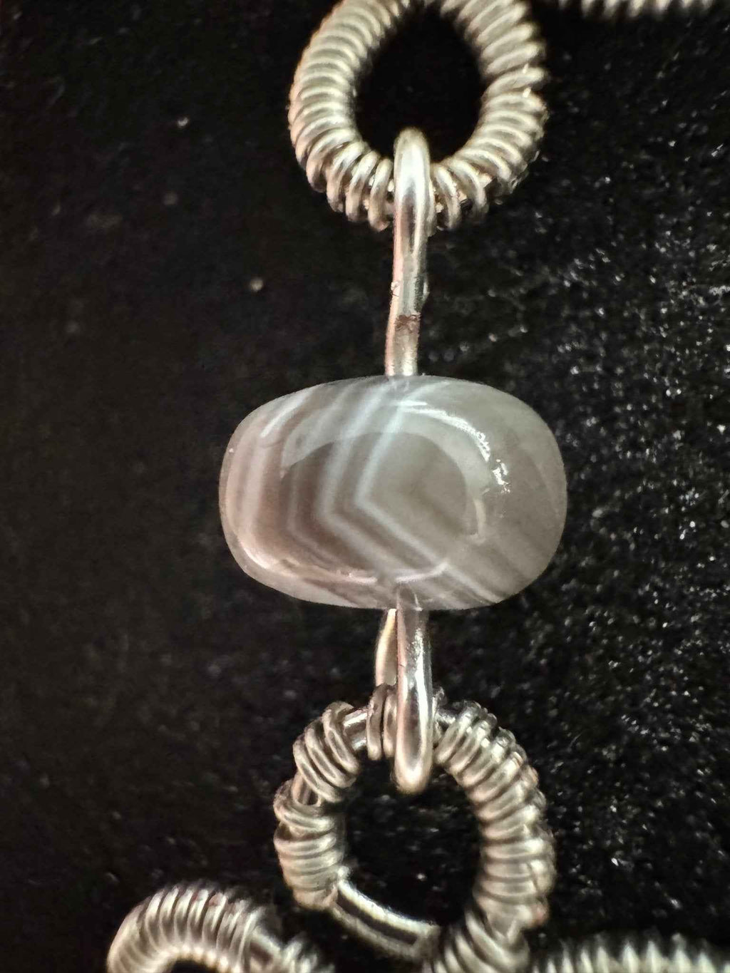 Close-up of silver clover wire wrapped earrings with Botswana Agate beads.