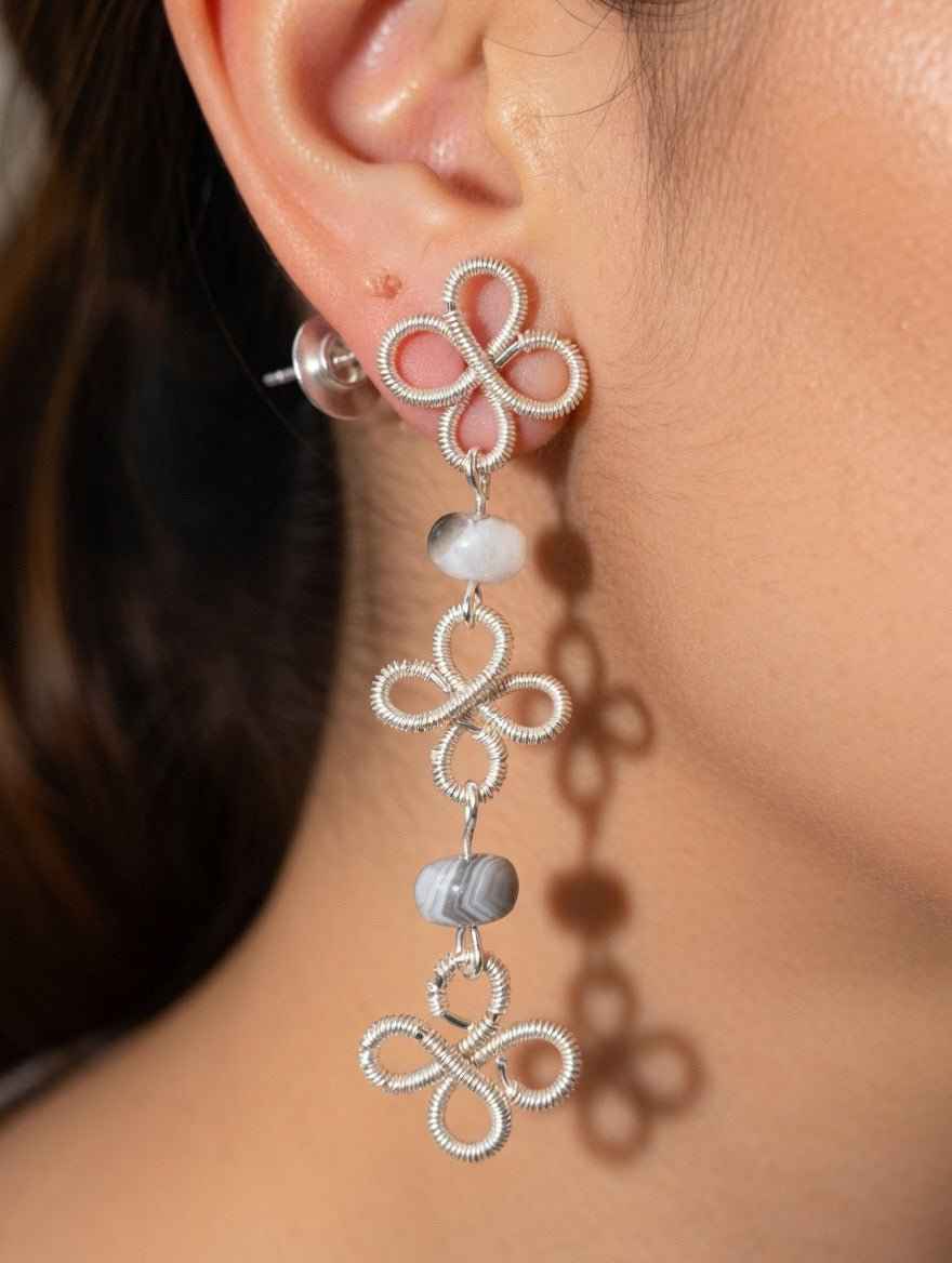 Close-up of a person wearing silver clover wire wrapped earrings with Botswana Agate beads.