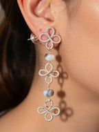 Close-up of a person wearing silver clover wire wrapped earrings with Botswana Agate beads.